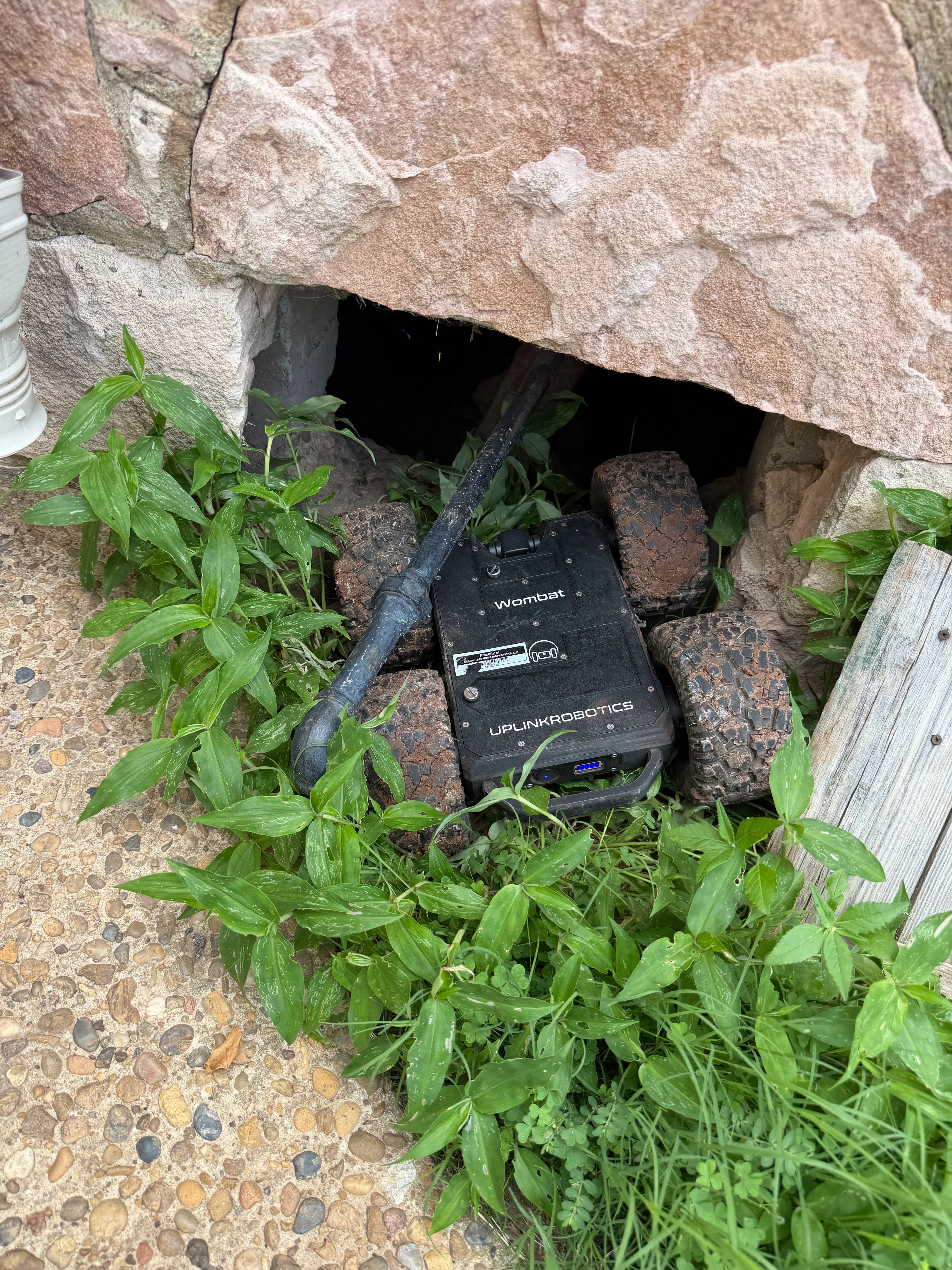 A remote crawler robot at the opening of a tight crawlspace before an inspection